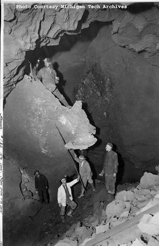 Underground photo of a massive piece of copper and miners at one of the Ahmeek mine shafts. (Photo courtesy of the MTU Archives, Keweenaw Digital Archives)